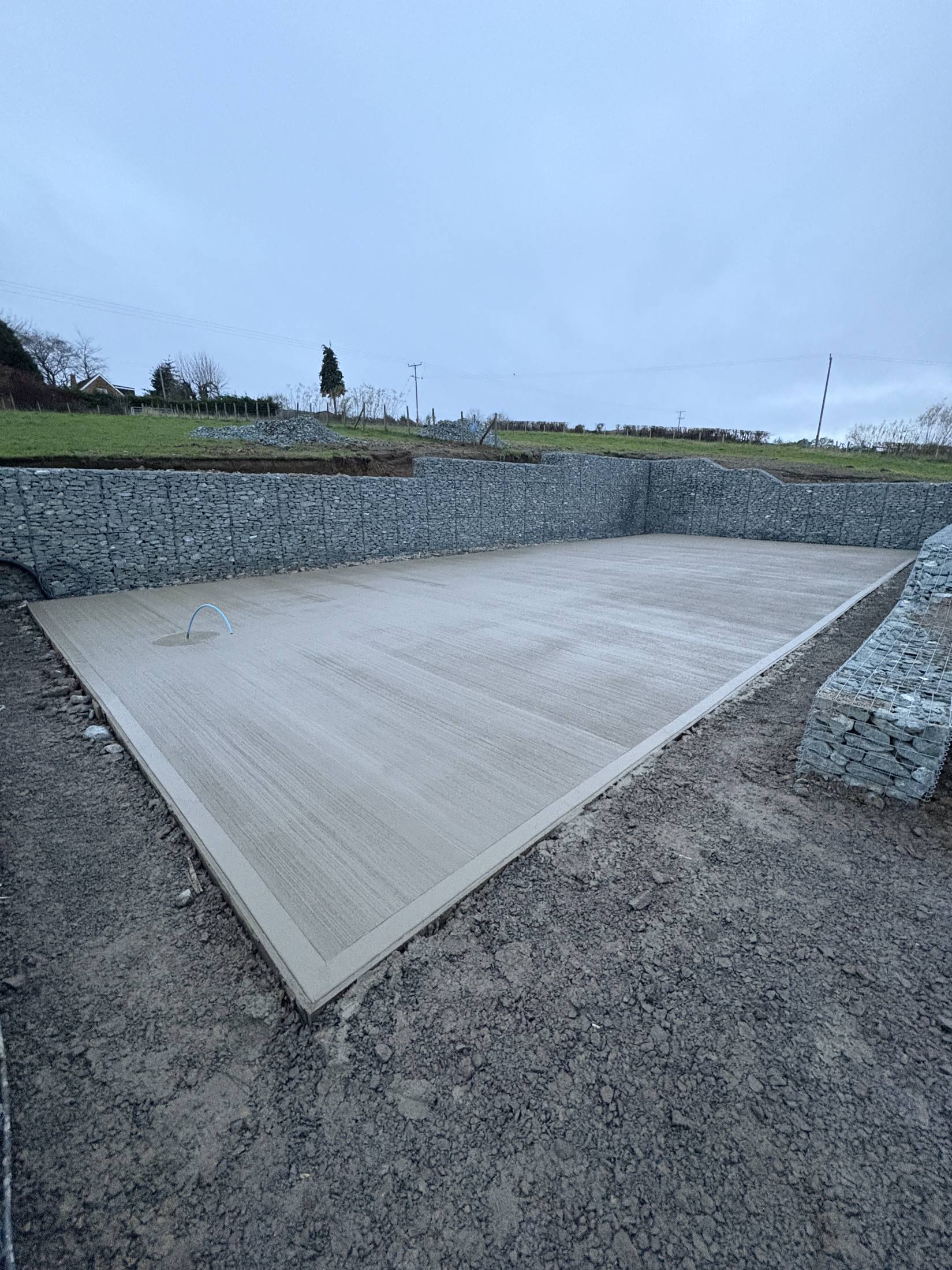 Brushed concrete slab finish inside gabion retaining walls