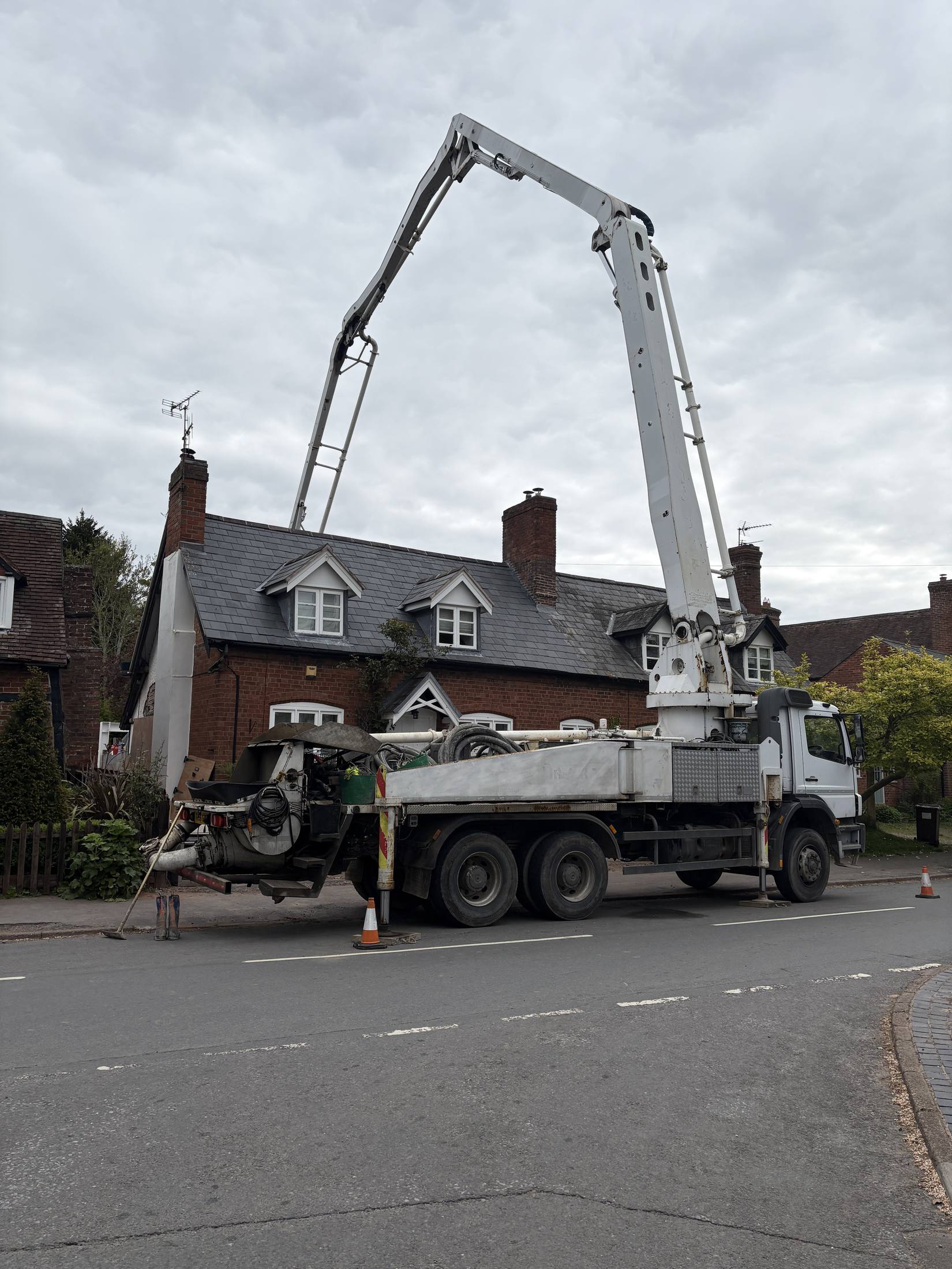 S. Wilkes Concrete Pumping boom pump fully extended over rooftops in a Shropshire village